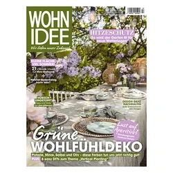 Titelseite des Magazins WOHN IDEE mit einem gedeckten Gartentisch mit grün-weißen Geschirr, geflochtenen Platzsets und Gläsern, umgeben von Fliederbüschen und Laternen. Schlagzeilen: 'HITZESCHUTZ' und 'Grüne WOHLFÜHLDEKO'.