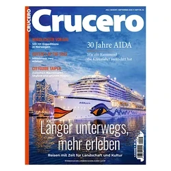Magazincover „Crucero“ mit dem nachts beleuchteten Kreuzfahrtschiff „AIDAperla“ mit Kussmund-Logo im Hafen vor einer Stadtkulisse. Titel: „Länger unterwegs, mehr erleben“.