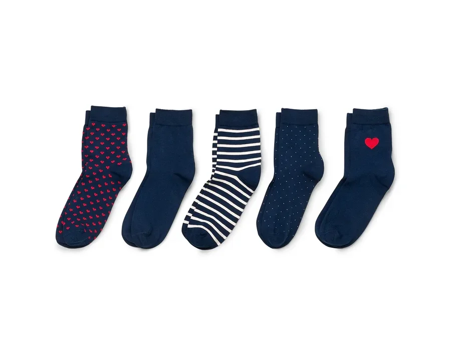 Fünf Paar marineblaue Socken mit roten Herzen, Streifen und Punkten liegen auf weißem Grund.