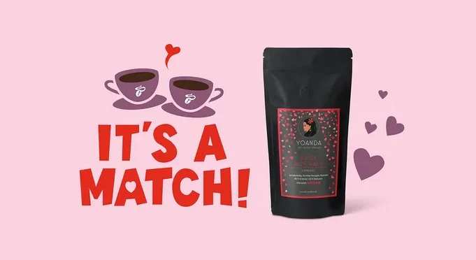 Auf rosa Hintergrund stehen zwei Tassen mit dem Schriftzug "It's a Match!" und eine Packung Yoanda Kaffee.