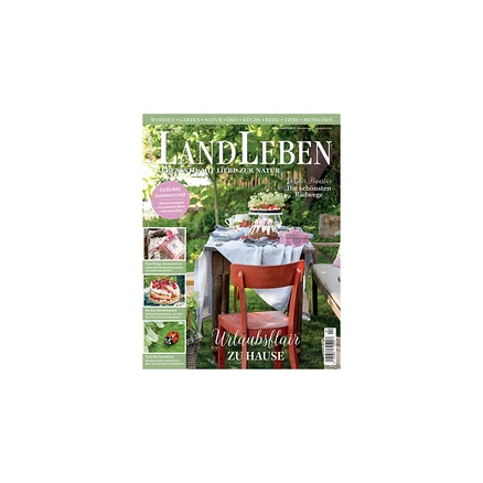 Magazincover „LANDLEBEN“ mit einem gedeckten Gartentisch, einem Kuchen mit Beeren, Blumen und einem roten Stuhl. Überschrift: „Urlaubsflair ZU HAUSE“.
