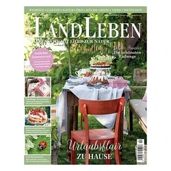 Magazincover „LANDLEBEN“ mit einem gedeckten Gartentisch, einem Kuchen mit Beeren, Blumen und einem roten Stuhl. Überschrift: „Urlaubsflair ZU HAUSE“.