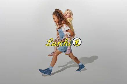 Eine junge Frau trägt ein Kind huckepack und geht. Beide tragen blaue Schuhe.