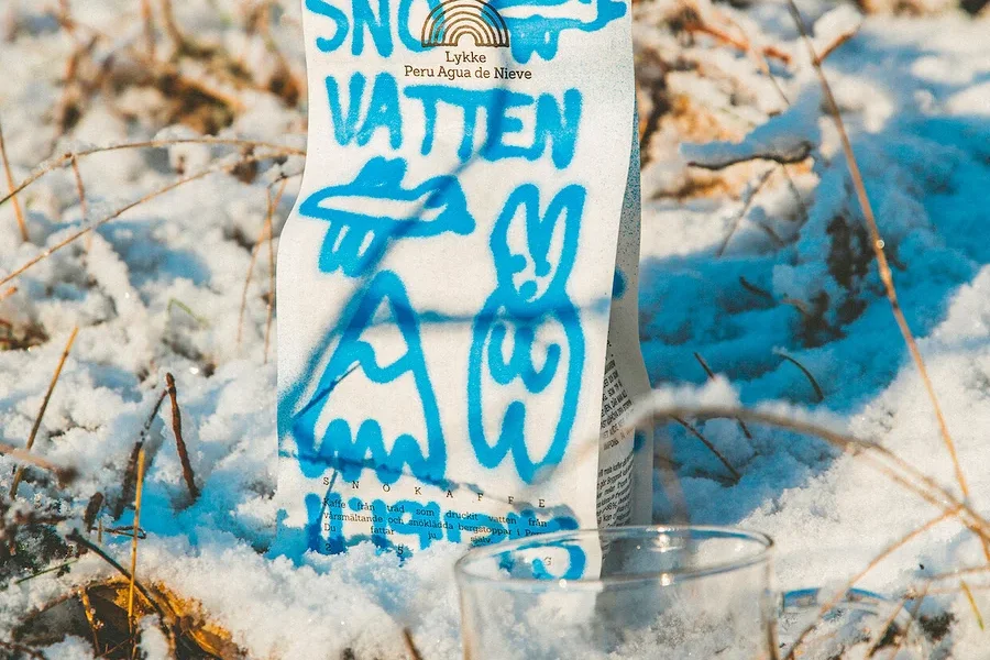 Eine Packung Lykke Peru Agua de Nieve Kaffee und ein Glas Kaffee stehen im Schnee.