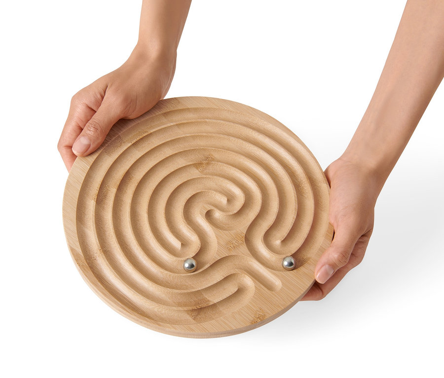 Hände halten ein Geduldsspiel »Labyrinth« mit zwei Metallkugeln.