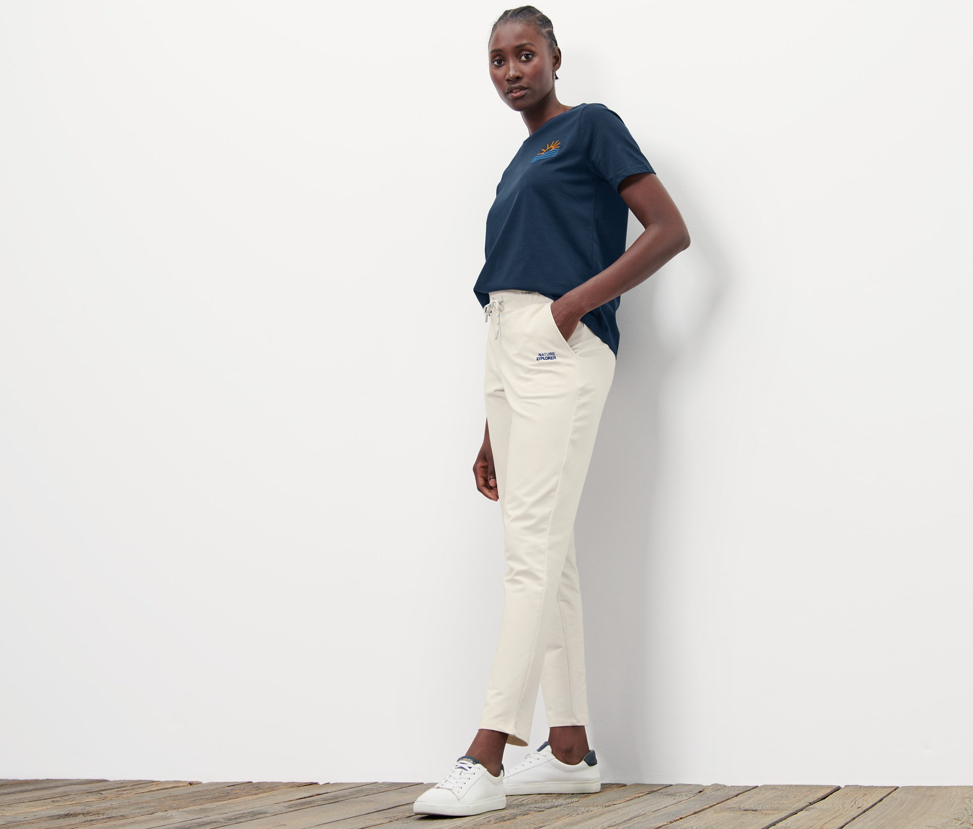 Frau posiert in beigen Joggpants und einem marineblauen T-Shirt.