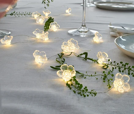 Eine LED-Microlichterkette Blumen liegt dekorativ auf einem Tisch.