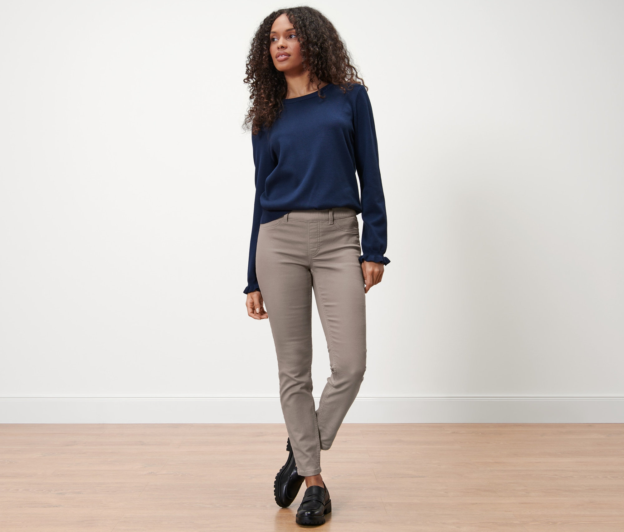 Frau steht in taupefarbenen Treggings – Fit »Nelly« und blauem Pullover auf dem Boden.