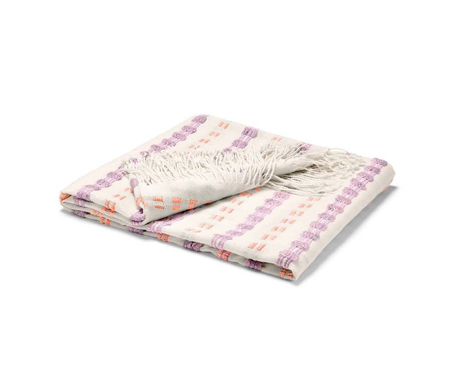 Zusammengefaltete Wohndecke mit Fransen und lila-orangen Mustern.