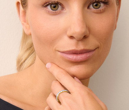 Frau mit blonden Haaren berührt ihr Kinn mit der Hand, an der sie einen vergoldeten 925 Silber Ring Memory trägt.