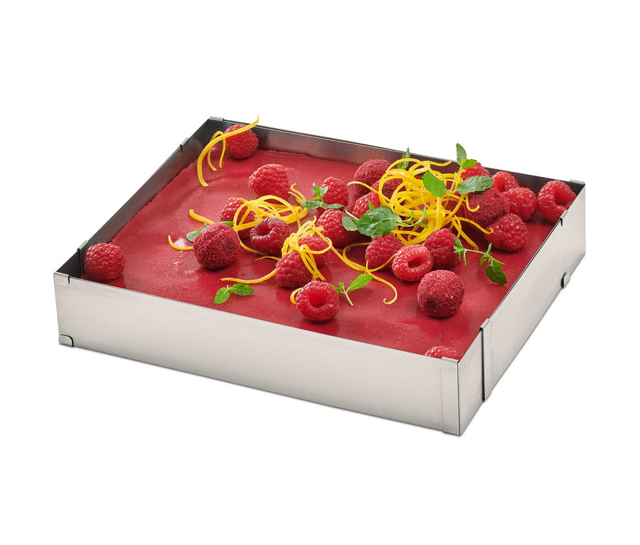 Quadratischer Edelstahl-Backrahmen mit Himbeeren, Zitronenschale und Minze.