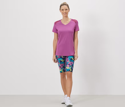 Frau trägt ein Sportshirt und geblümte Shorts.