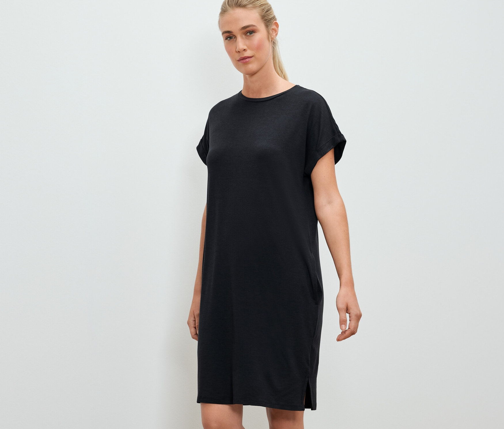 Frau posiert in einem schwarzen Outdoor-Kleid.