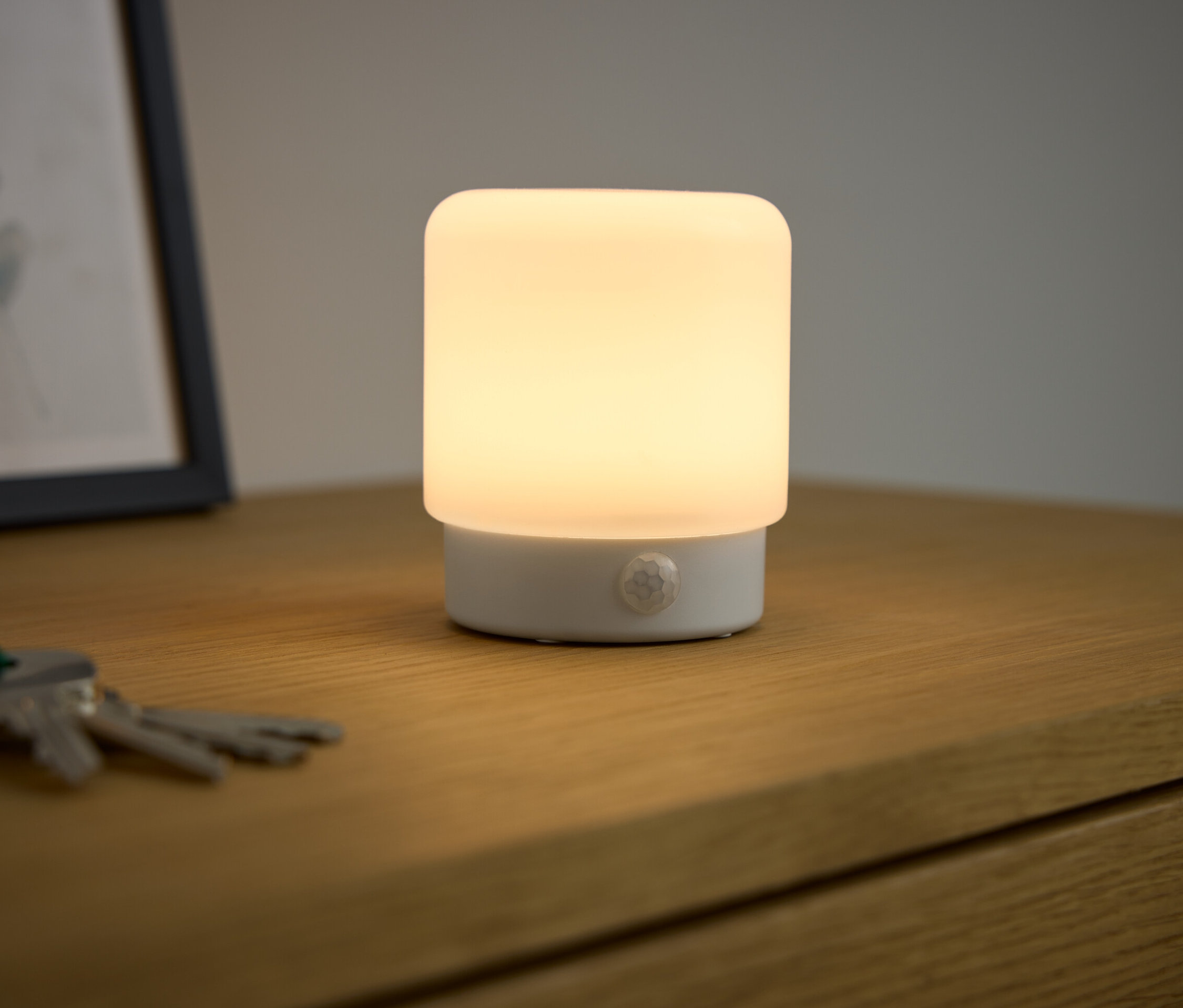 LED-Mini-Multifunktionslicht mit Bewegungsmelder leuchtet auf einem Nachttisch.