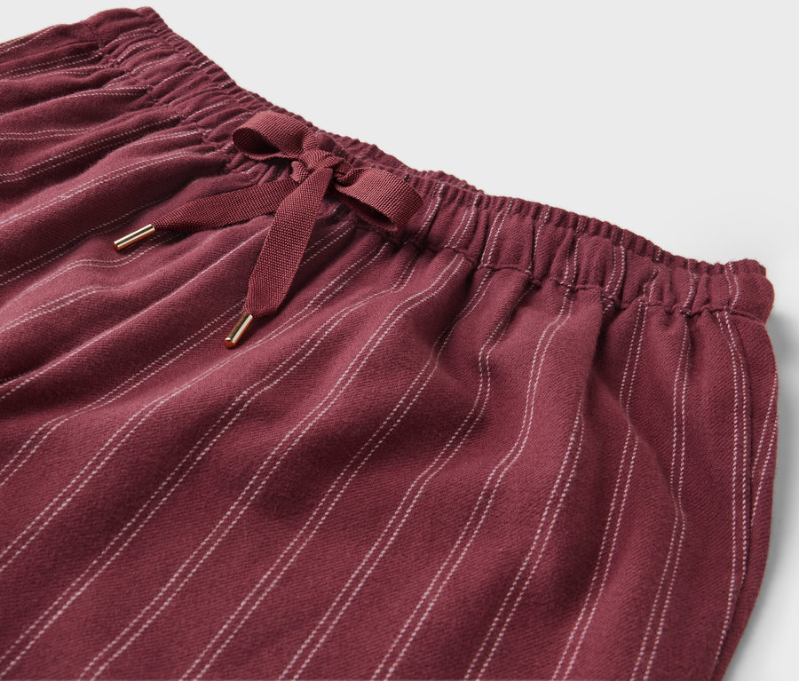 Detailaufnahme einer weinroten, gestreiften Hose mit Schleife in der Taille.
