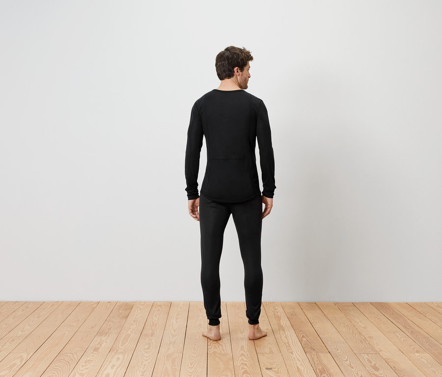 Ein Mann steht mit dem Rücken zur Kamera und trägt schwarze Thermobekleidung.