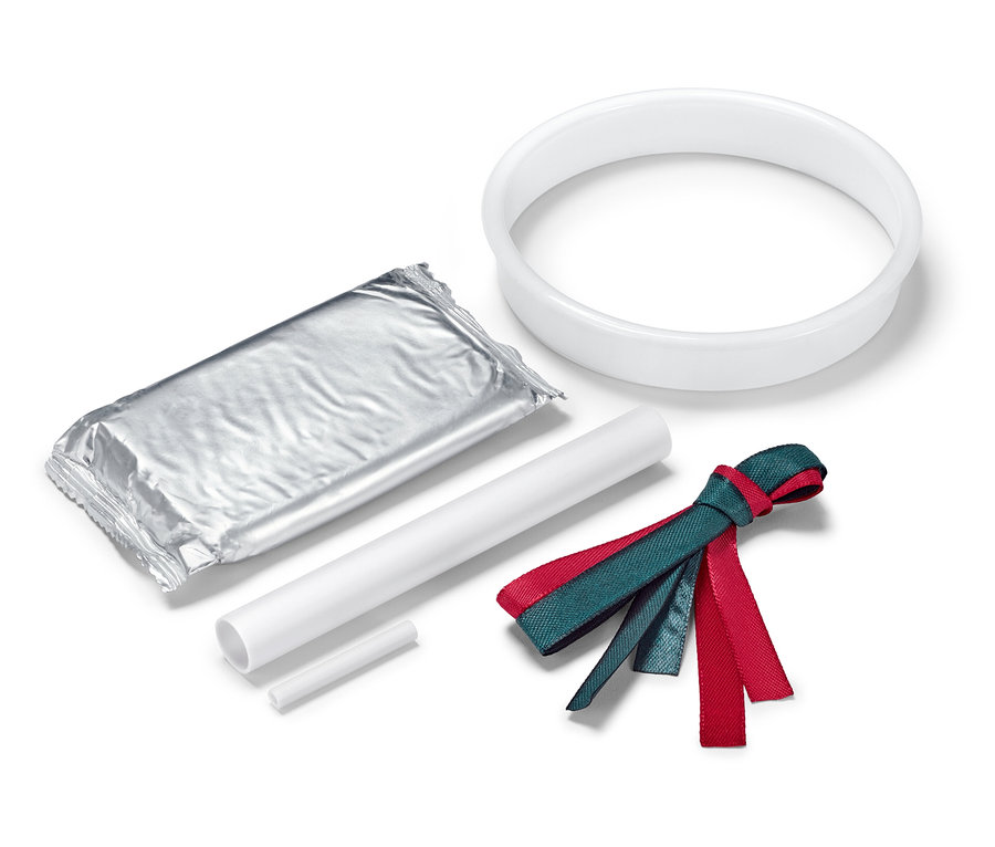 Eine silberne Verpackung, ein weißer Kreis, zwei weiße Stäbe und ein rot-grünes Band auf weißem Hintergrund.