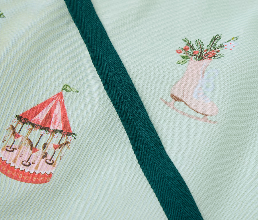 Hellgrüner Stoff bedruckt mit Karussell, Schlittschuhen mit Blumen und Lebkuchenhaus.
