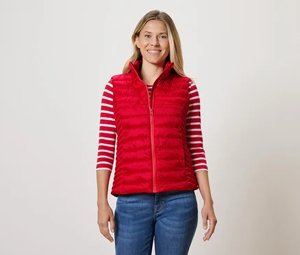 Frau trägt eine rote Steppweste, ein gestreiftes T-Shirt und Jeans.