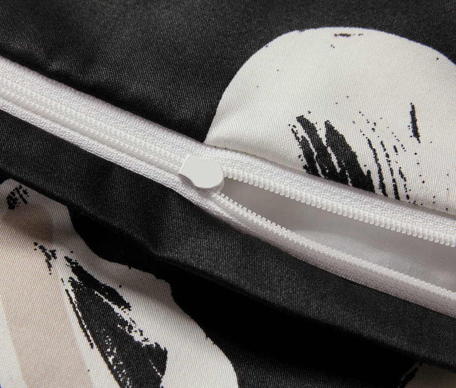 Detailaufnahme eines schwarz-weißen Bettbezugs mit teilweise geöffnetem Reißverschluss.