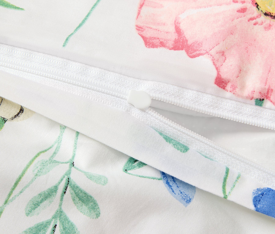 Detailansicht eines weißen Bettbezugs mit Blumenmuster und Reißverschluss.