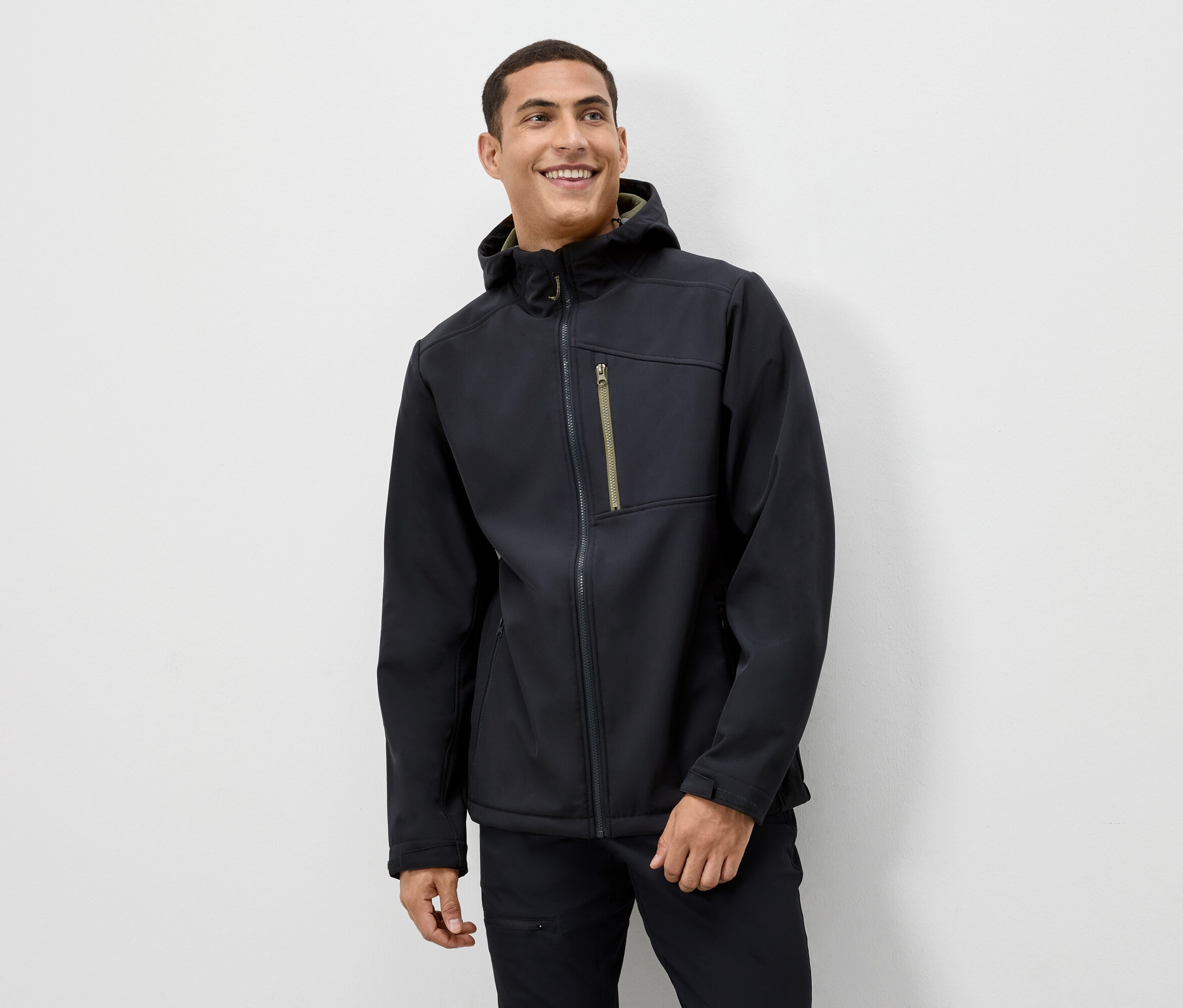 Mann lächelt und trägt eine schwarze Jacke mit Kapuze.