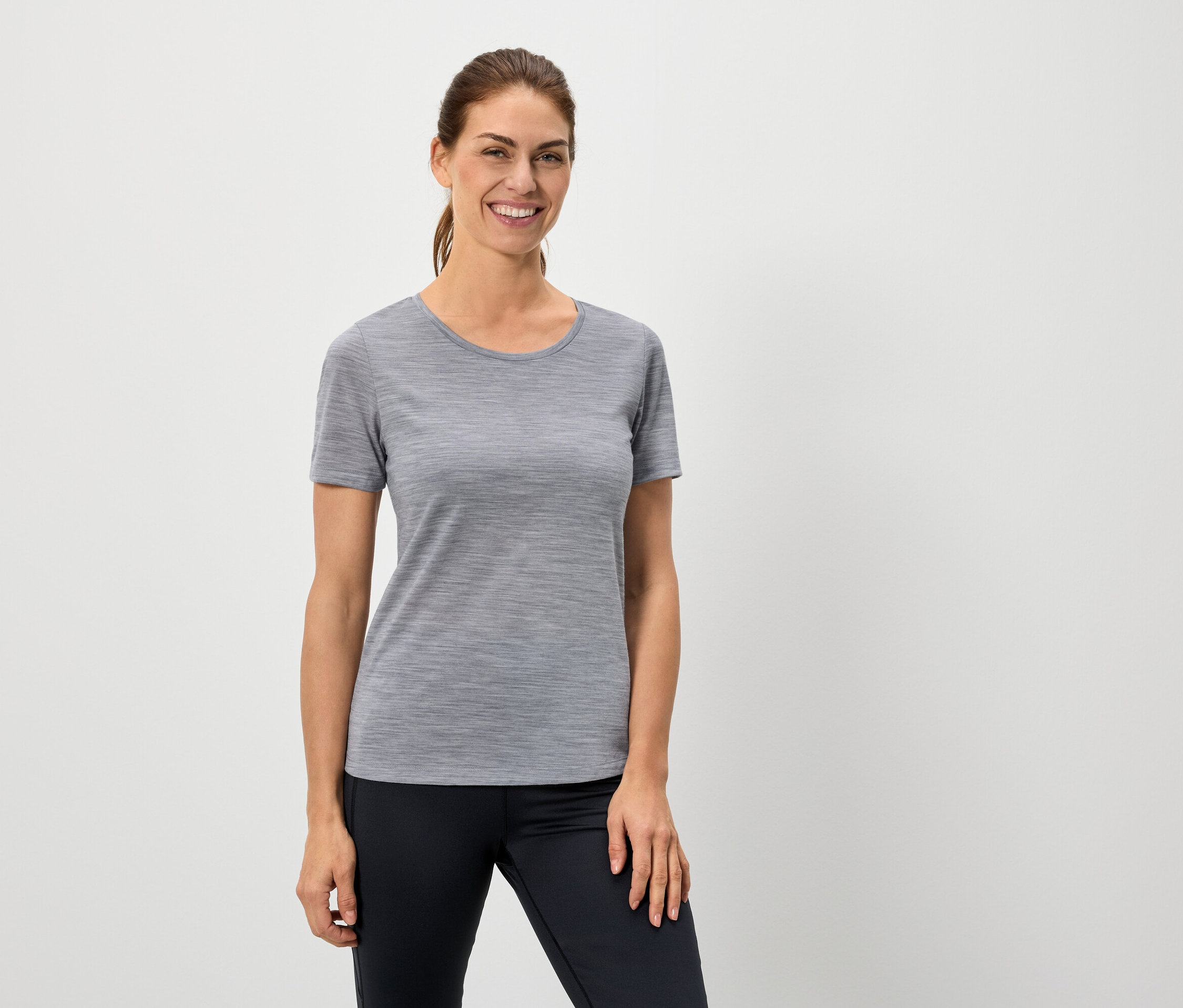 Frau trägt ein graues T-Shirt und schwarze Leggings.
