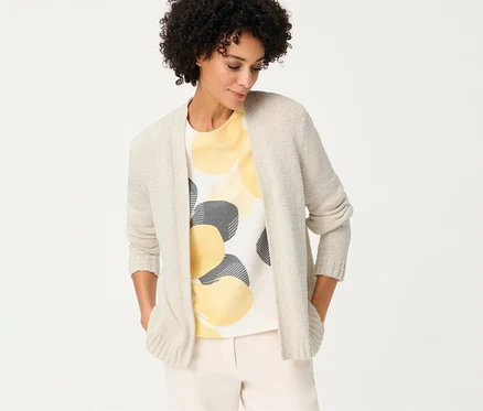 Frau mit Olsen Leinen-Cardigan über einem T-Shirt mit gelben und grauen Kreisen, die ihre Hände in den Taschen hat.