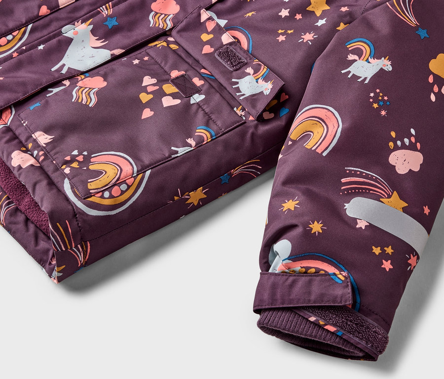 Nahaufnahme einer lila Jacke mit Einhorn-, Regenbogen- und Sternmuster, die Taschen und einen Ärmel zeigt.