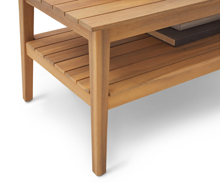 Nahaufnahme eines hellbraunen Holzbeistelltisches mit Ablagefläche und Buch darauf.