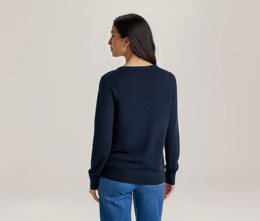 Frau von hinten, trägt einen dunkelblauen Langarmpullover und blaue Jeans.