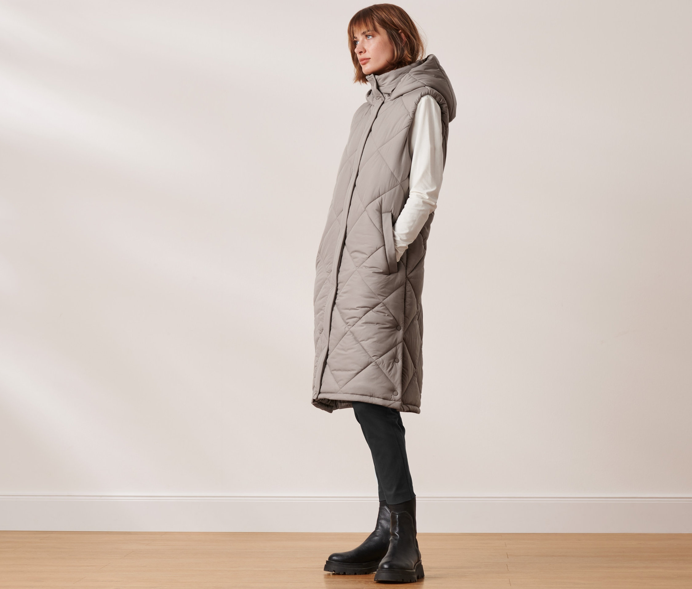 Frau trägt lange Steppweste mit Kapuze.