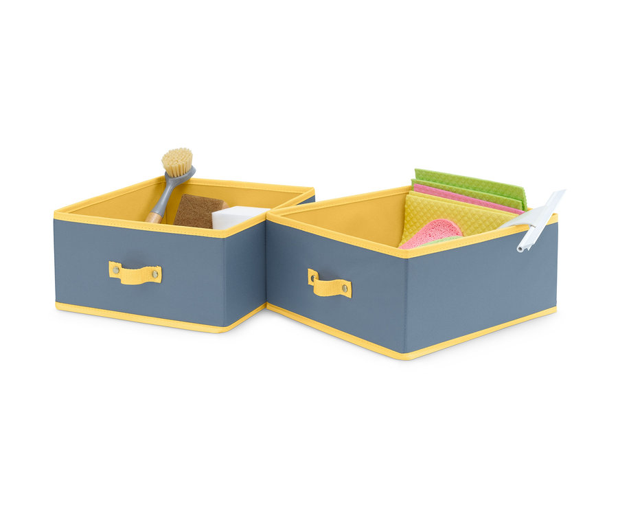Zwei große Schubladen-Ordnungsboxen, grau mit gelbem Rand, eine mit Bürste, Schwamm und weißem Würfel, die andere mit Tüchern und Abzieher.