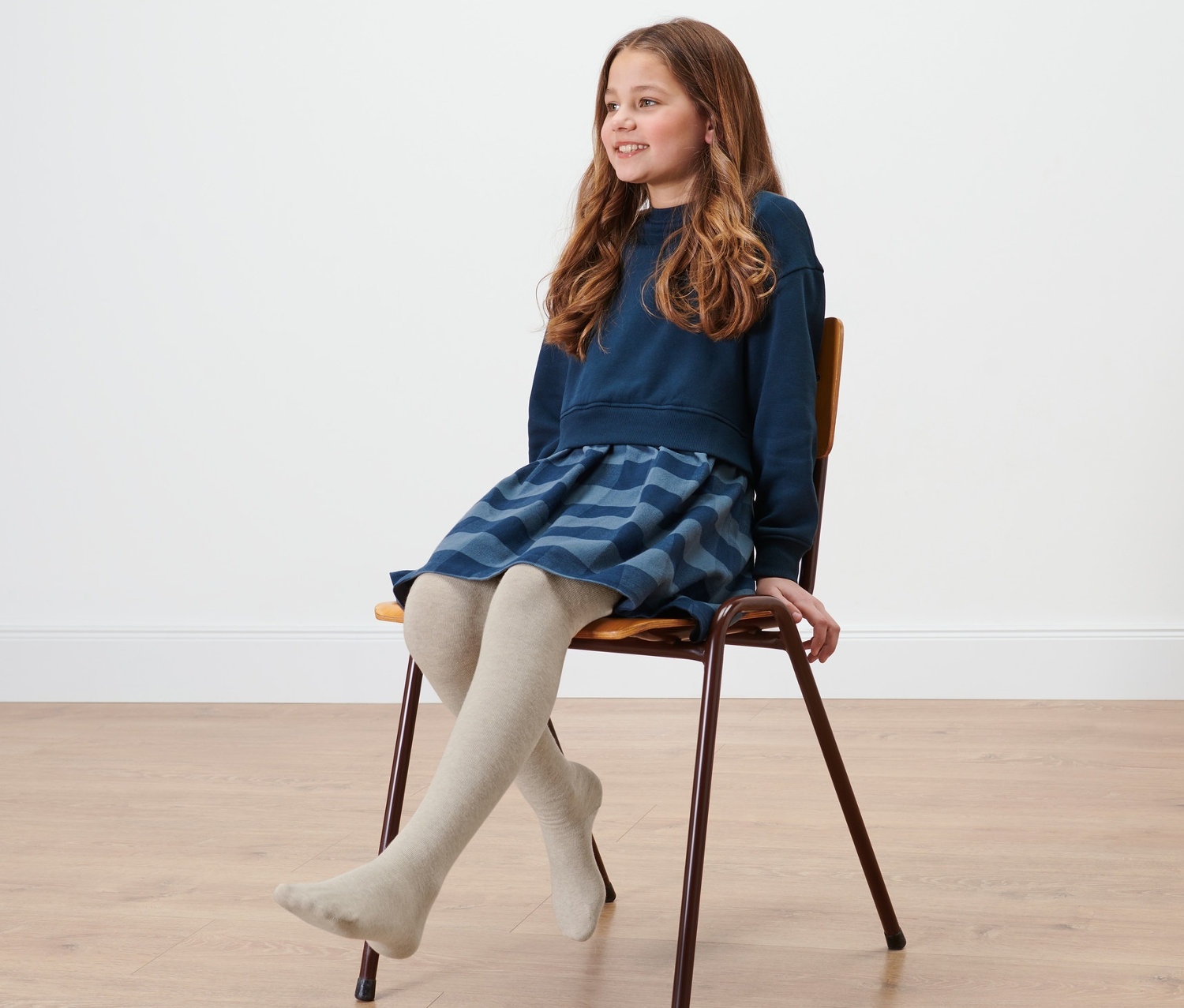 Mädchen sitzt auf Stuhl und trägt 5 Paar Kinder-Strumpfhosen.