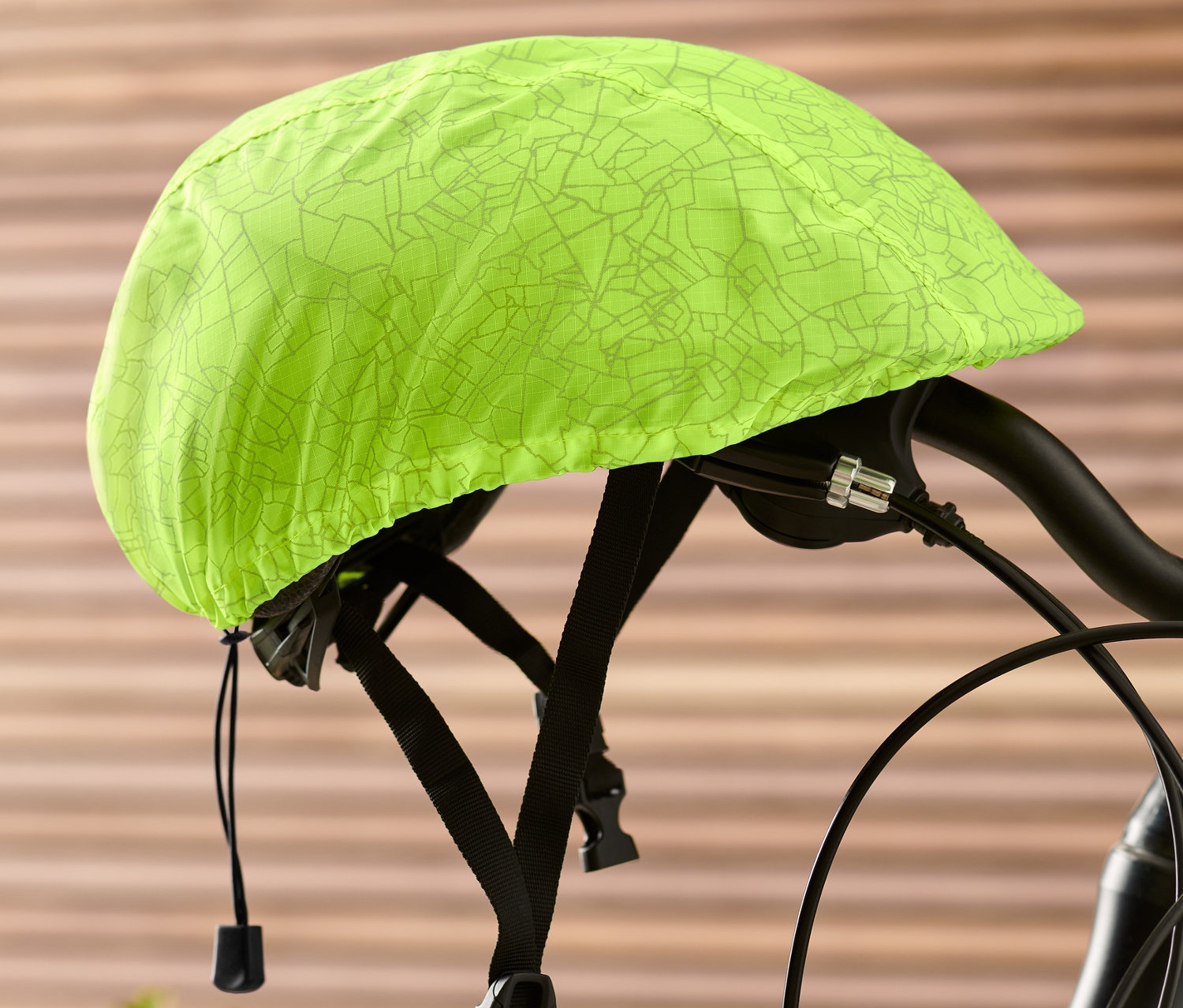 Ein neongelber Fahrradhelm-Überzug ist auf einem Fahrradlenker befestigt.