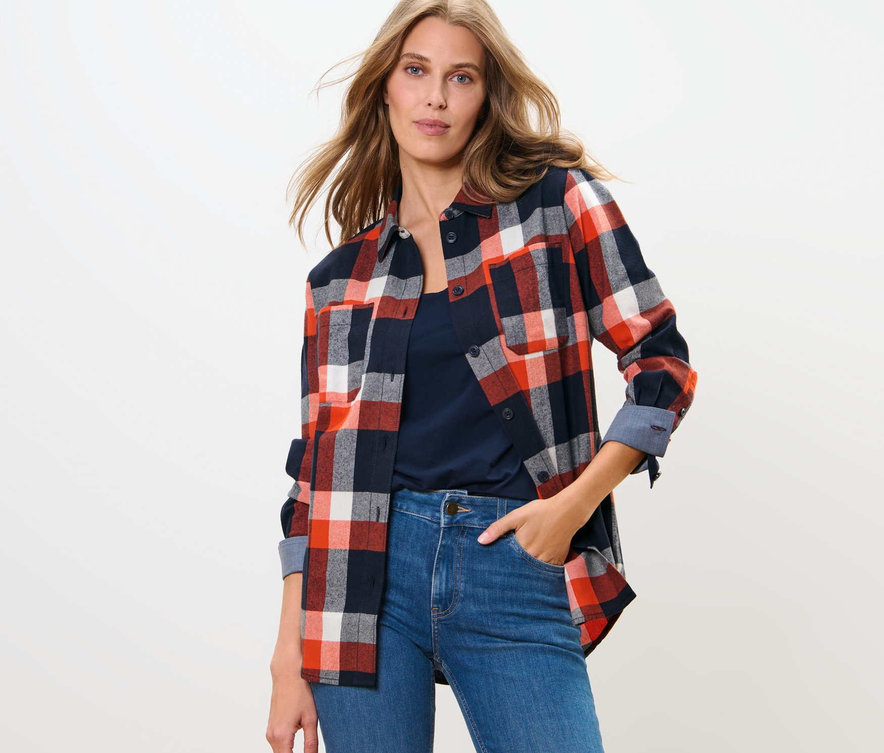 Frau posiert in Karo-Bluse und Jeans.