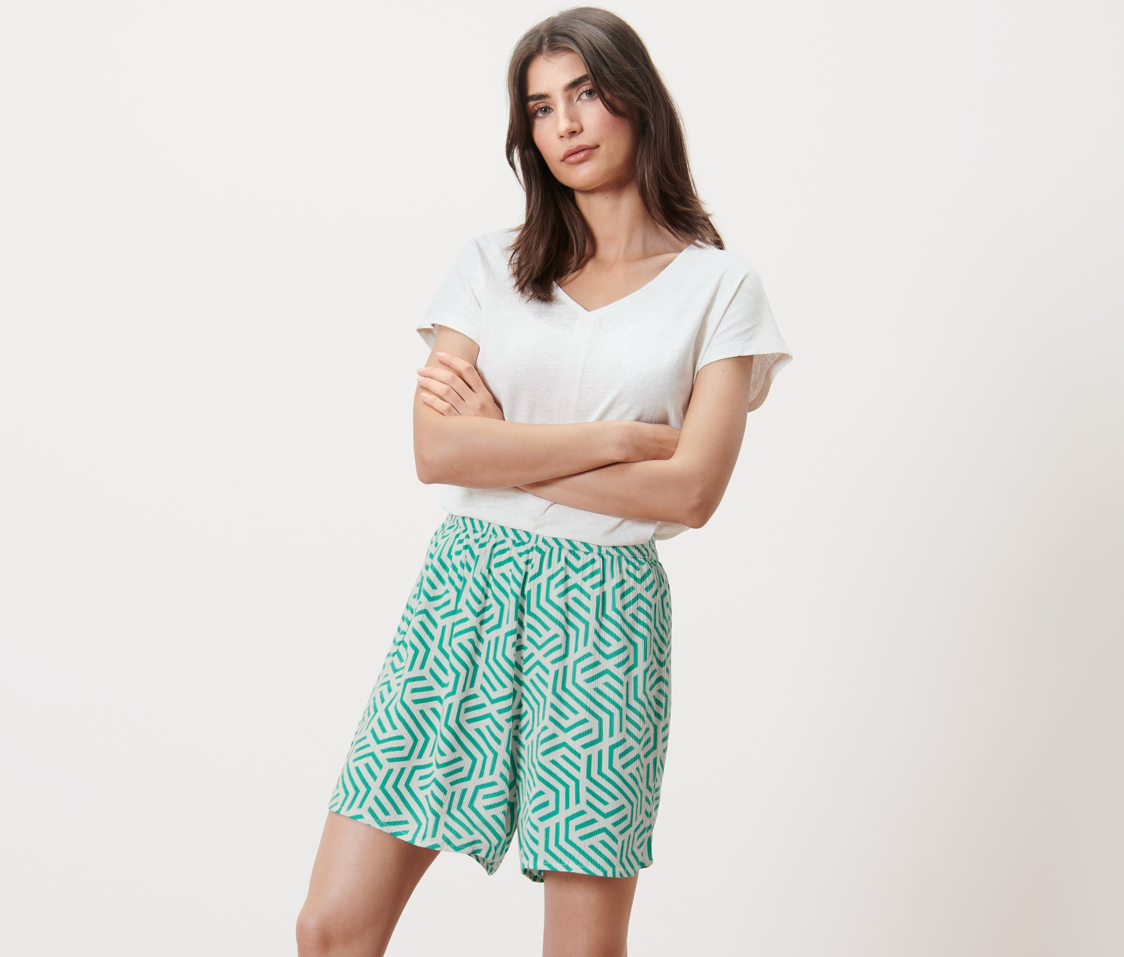 Frau posiert mit verschränkten Armen in bedruckten Webshorts.