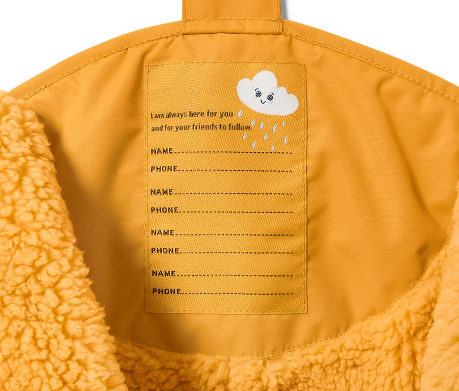 Detail einer maisgelben Kleinkind-Thermo-Regenhose mit Etikett für Name und Telefonnummer.