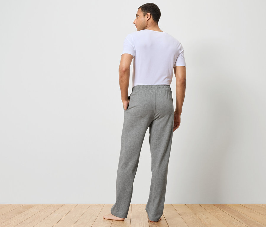 Mann von hinten trägt graue Jogginghose und ein weißes T-Shirt.