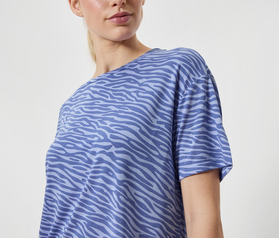 Frau trägt blaues T-Shirt mit Tiermuster.