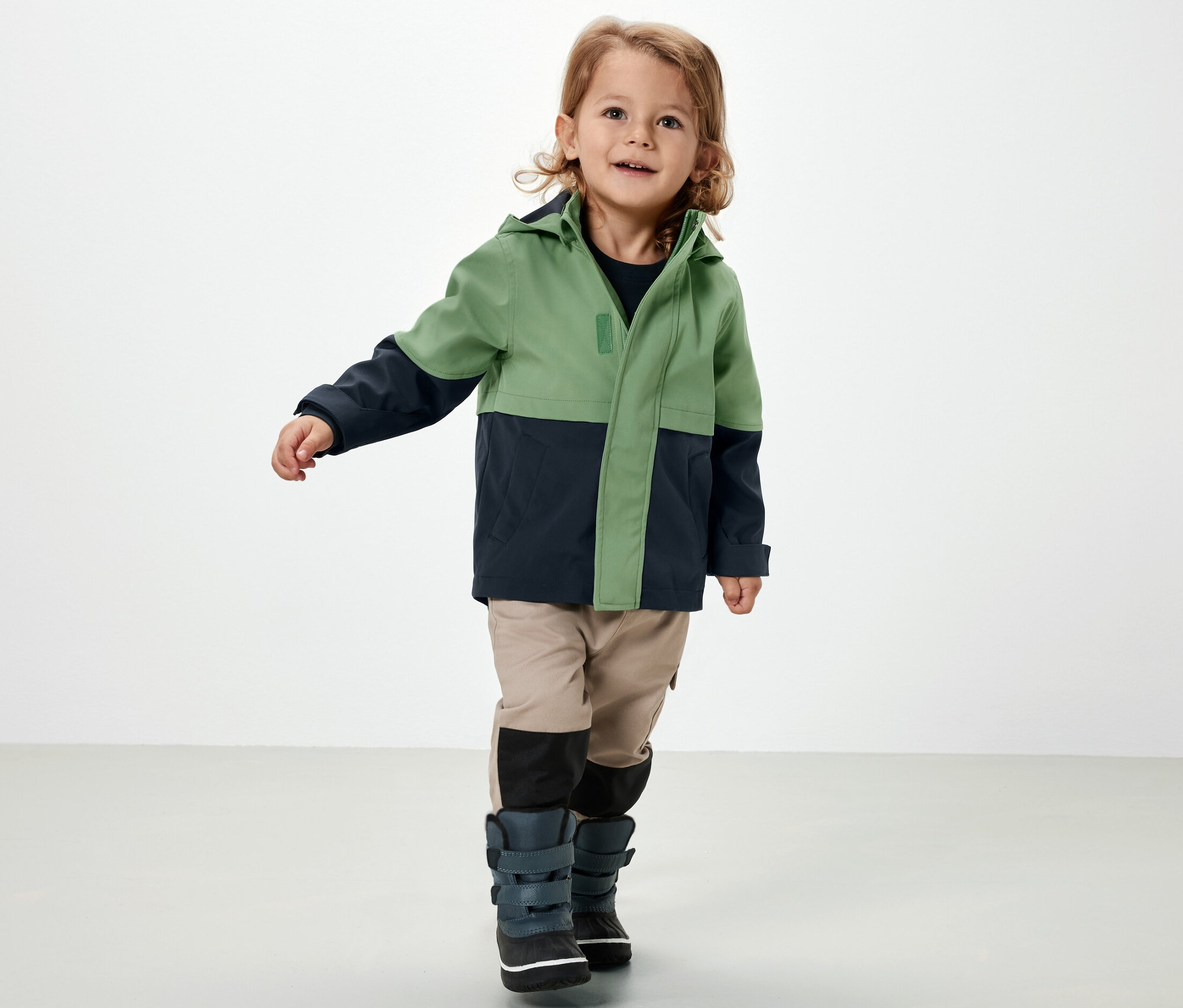 Ein Junge trägt eine Kinder-Softshelljacke.