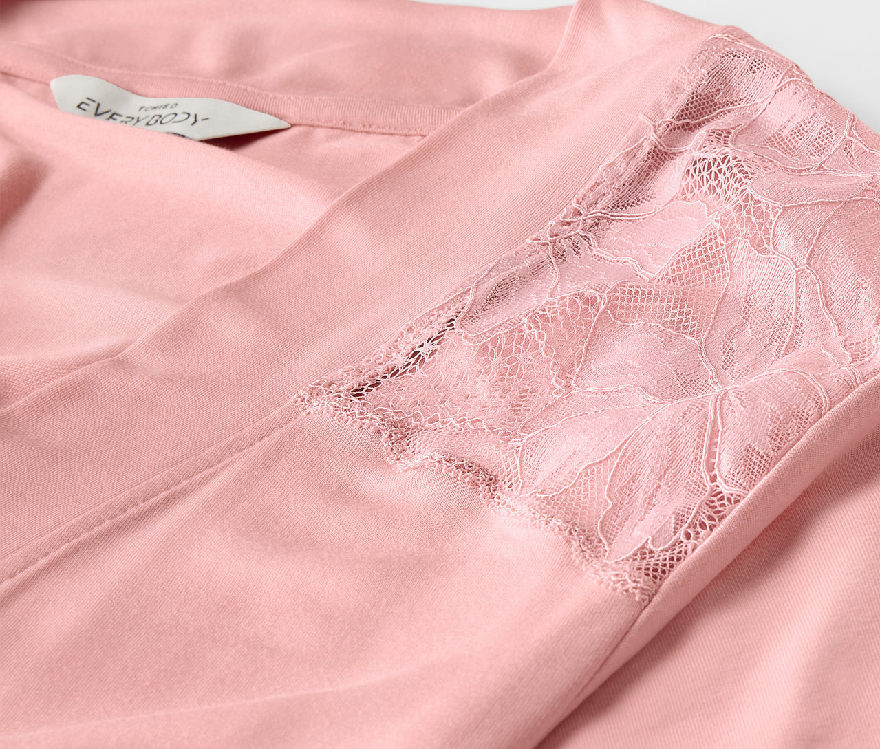Detailansicht eines rosa Morgenmantels mit Spitze am Ärmel.