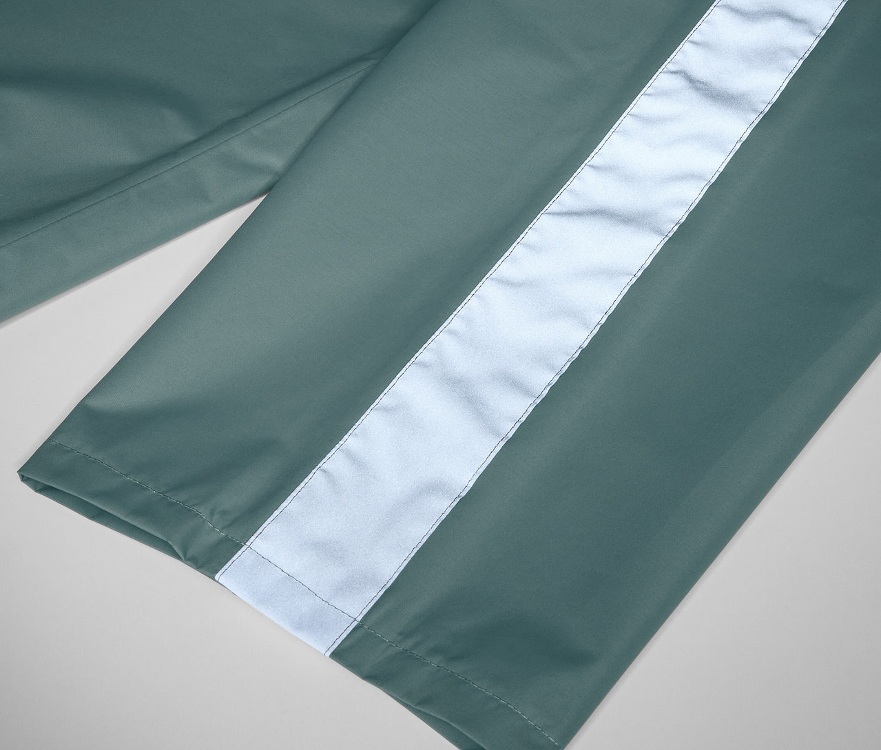 Detailaufnahme einer Kinder-Regenhose in Salbeigrün mit Reflexstreifen.