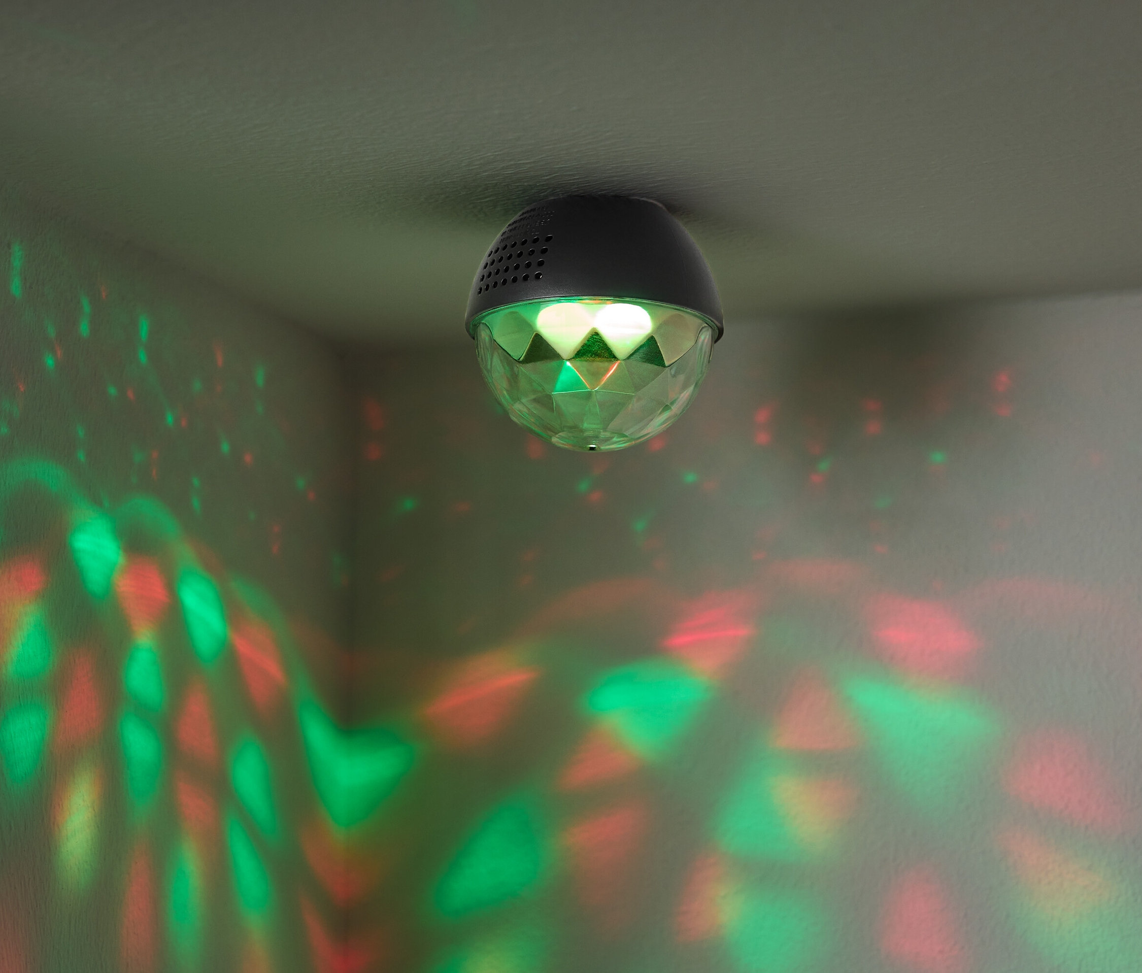 Eine an der Decke befestigte Discokugel wirft rote und grüne Lichter an die Wände.