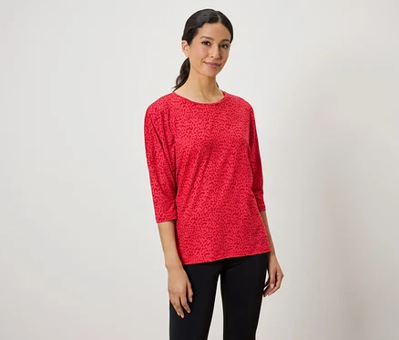 Frau trägt ein rotes Oberteil mit Tiermuster und schwarze Leggings.