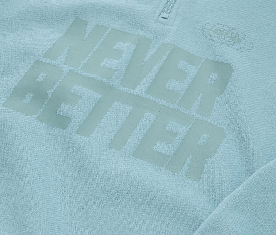 Nahaufnahme eines hellblauen Sweatshirts mit dem Aufdruck "NEVER BETTER" und einem Reißverschluss am Kragen.