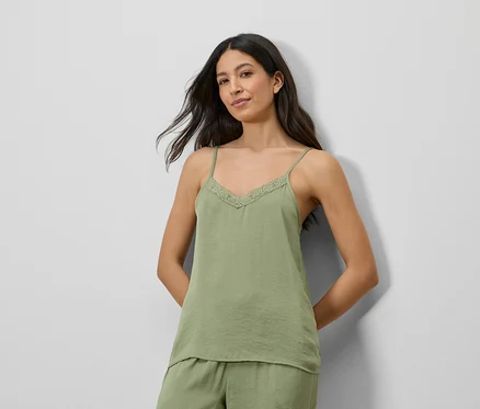 Frau trägt ein grünes Satin-Top mit Spitze und passende Shorts.