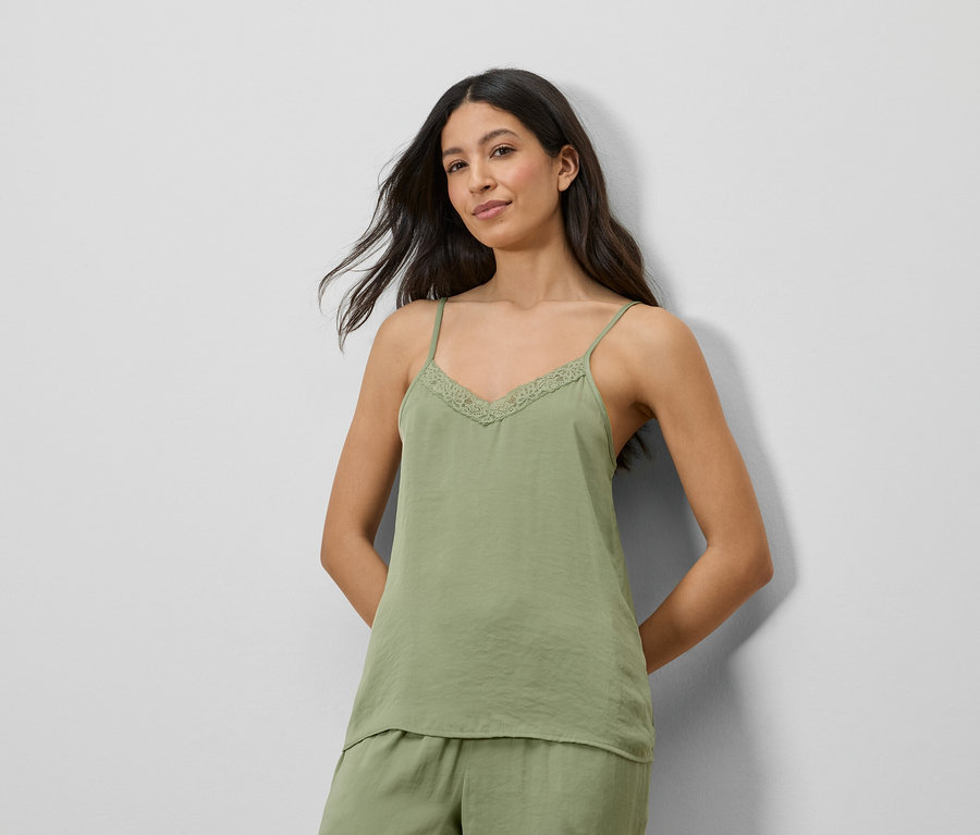 Frau trägt ein grünes Satin-Top mit Spitze und passende Shorts.