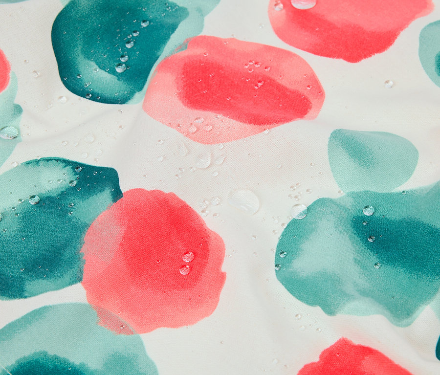 Nahaufnahme von Stoff mit rosa und türkisfarbenen Blüten und Wassertropfen.