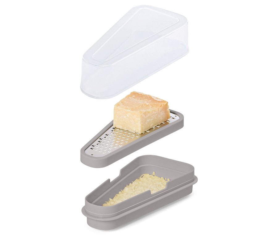 Ein graues Käsereibe-Set mit einem Stück Käse auf der Reibe, geriebenem Käse im Behälter und einem transparenten Deckel darüber.
